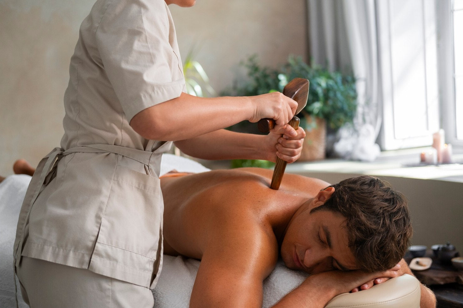 Person receiving a massage with a wooden tool in a spa setting