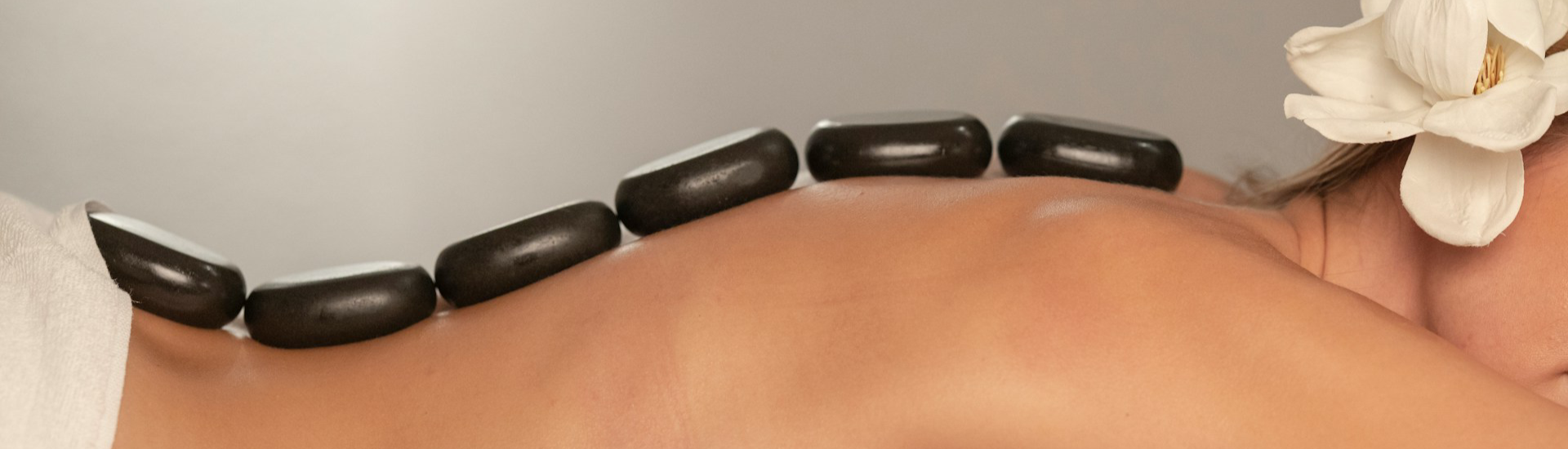 Person receiving hot stone massage on a neutral background