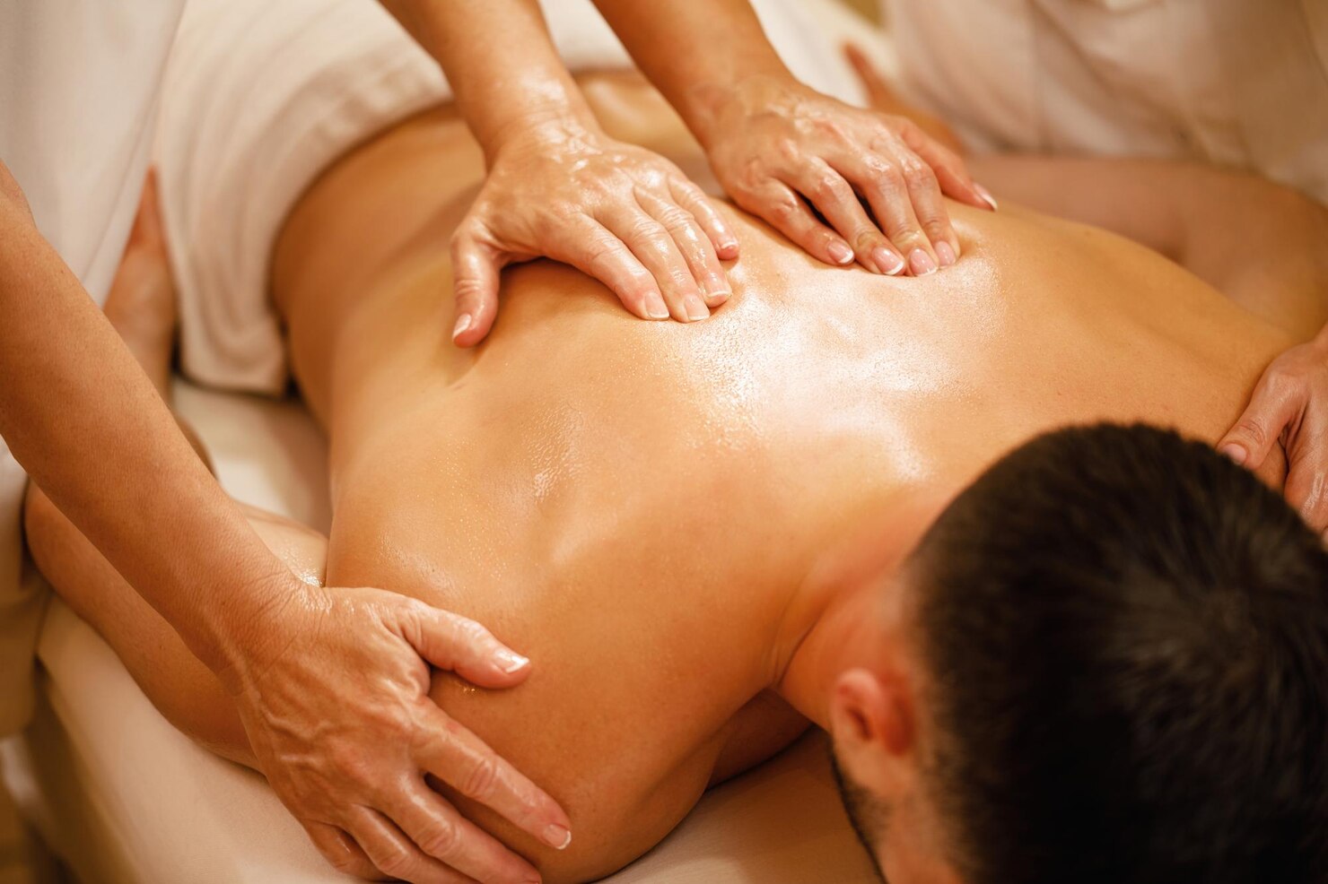 Person receiving a massage with hands applying oil on the back