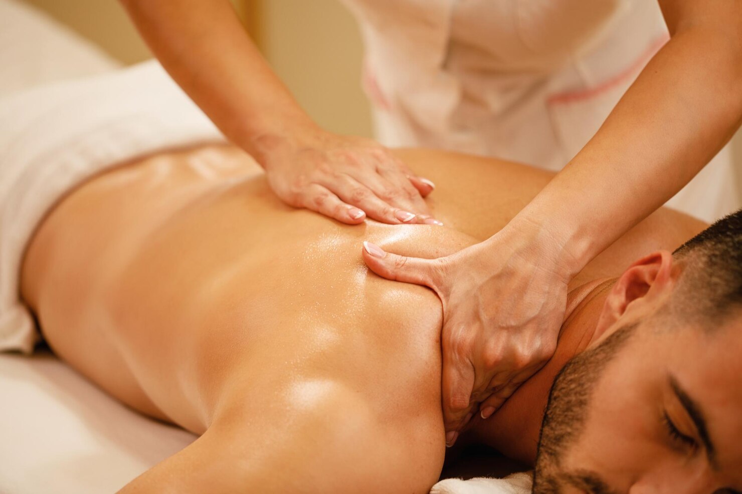 Person receiving a massage with hands applying pressure on the back.