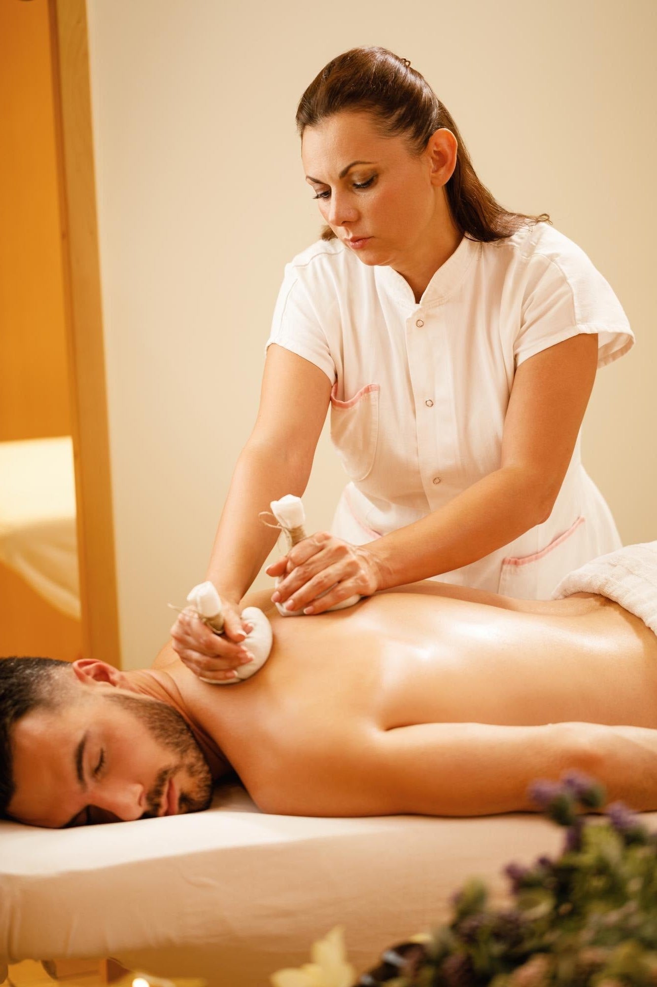 Woman giving a massage to a man in a spa setting